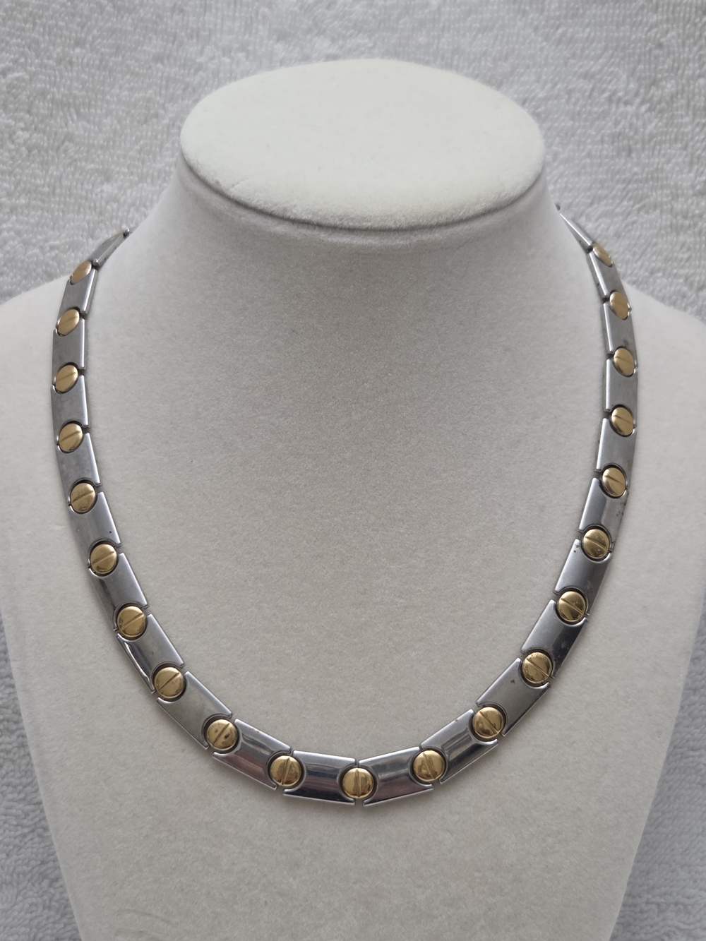 Two-tone, industrial-inspired design with gold-toned screw head motifs